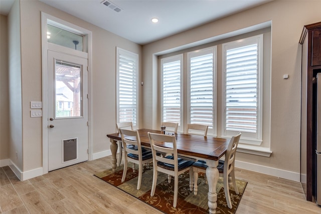 dining area with visible vents, light wood finished floors, and baseboards