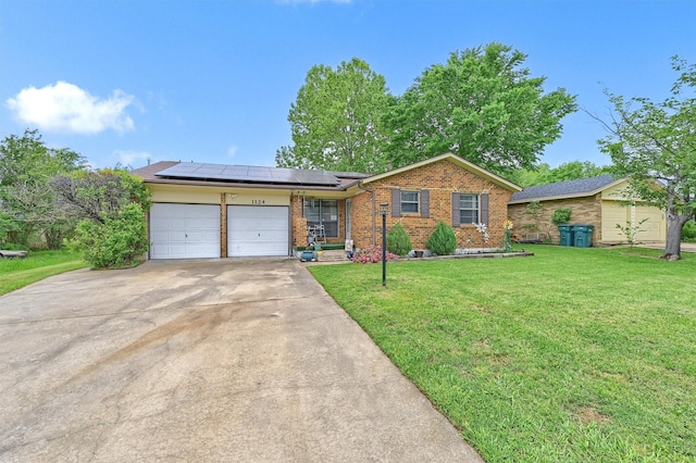 ranch-style home with an attached garage, solar panels, a front lawn, and brick siding