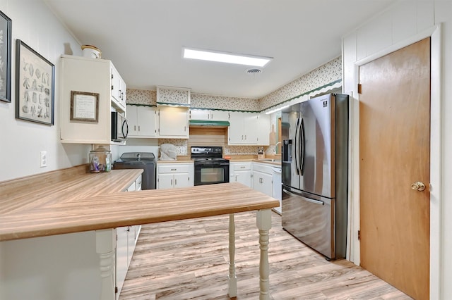 kitchen with black electric range oven, stove, light countertops, a sink, and stainless steel fridge