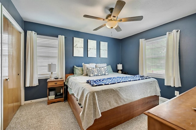 bedroom with light colored carpet, a ceiling fan, and baseboards
