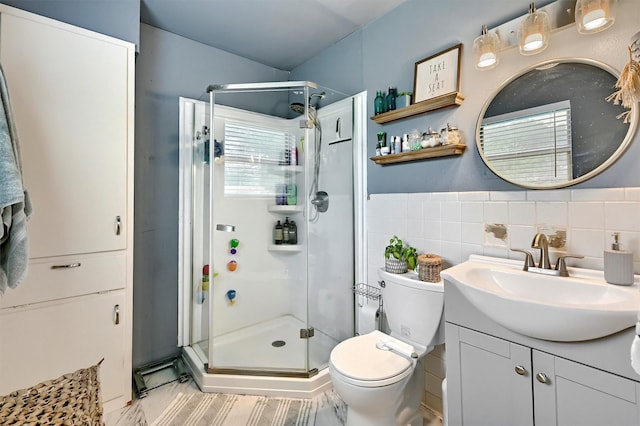 bathroom featuring vanity, tile walls, toilet, and a shower stall