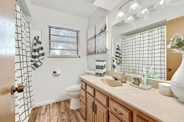 bathroom with wainscoting, curtained shower, wood finished floors, vanity, and toilet