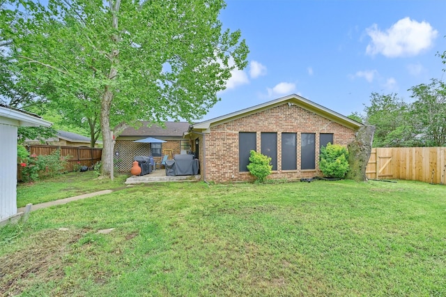 back of property with brick siding, a fenced backyard, a yard, and a patio