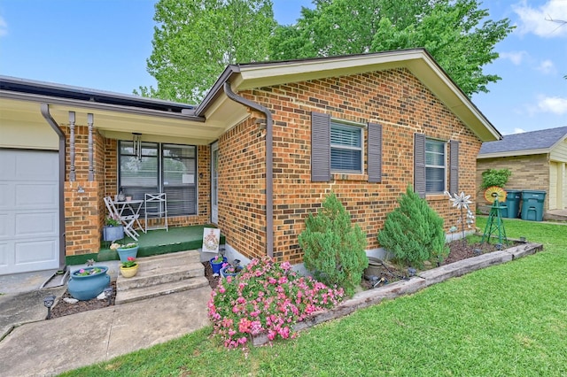 exterior space featuring a porch, a garage, a yard, and brick siding