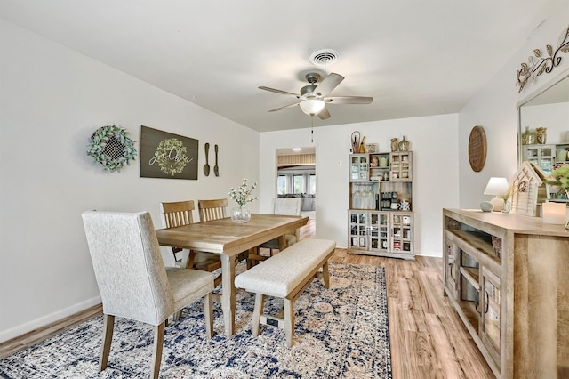 dining room featuring light wood-type flooring, baseboards, ceiling fan, and visible vents