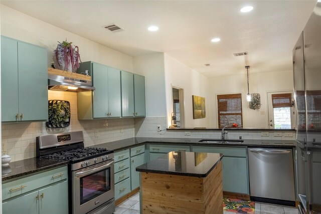 kitchen featuring visible vents, under cabinet range hood, tasteful backsplash, a sink, and stainless steel appliances