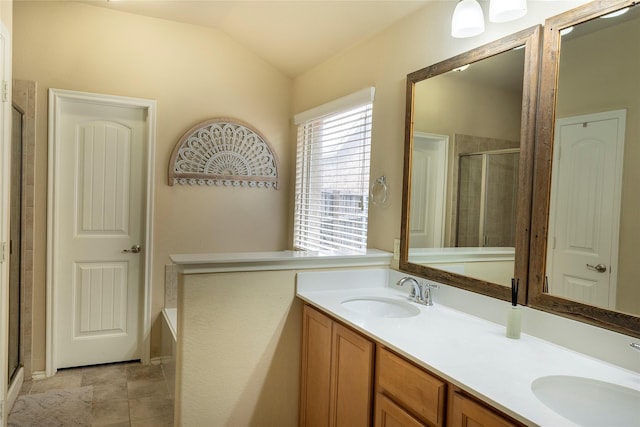 full bath featuring double vanity, vaulted ceiling, a shower stall, and a sink