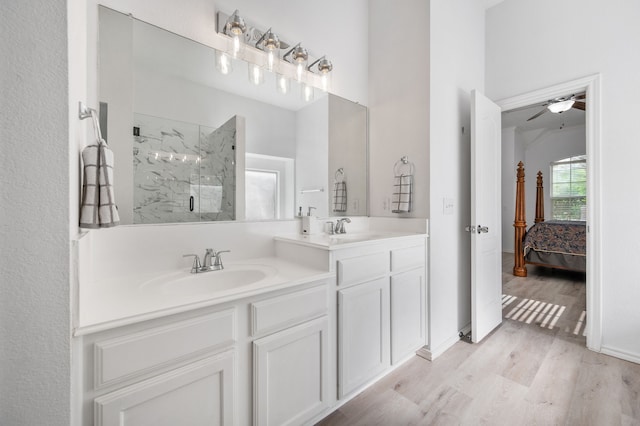 ensuite bathroom featuring vanity, wood finished floors, connected bathroom, a ceiling fan, and a marble finish shower