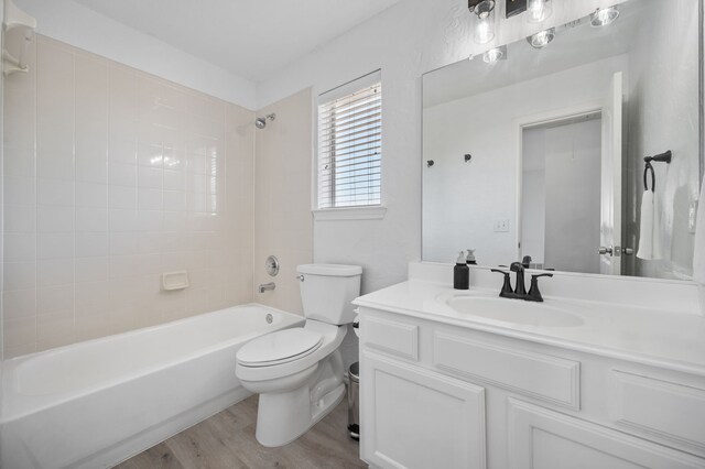 bathroom with toilet,  shower combination, wood finished floors, and vanity