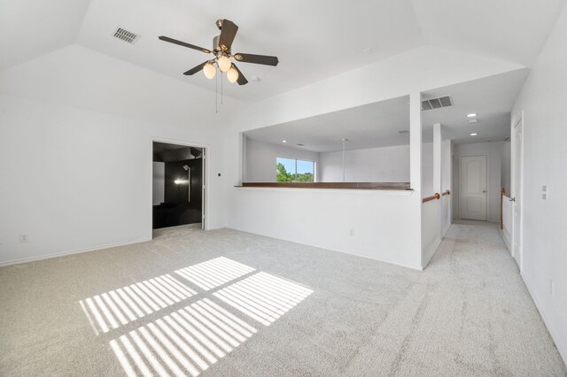 unfurnished room with light colored carpet, a ceiling fan, visible vents, and vaulted ceiling