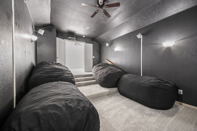 cinema with carpet, a textured wall, a ceiling fan, and vaulted ceiling