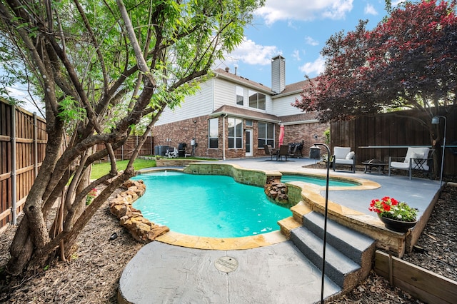 view of swimming pool with a fenced backyard, a pool with connected hot tub, a patio area, and cooling unit