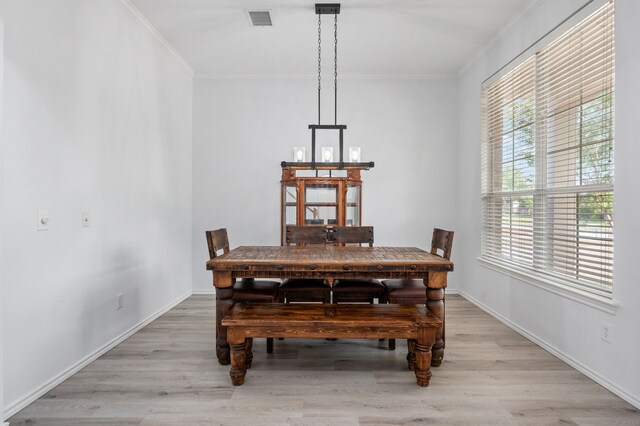 dining area featuring visible vents, ornamental molding, light wood-style floors, and baseboards