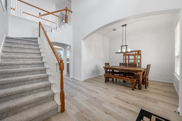 dining room with arched walkways, baseboards, light wood-style flooring, and stairway