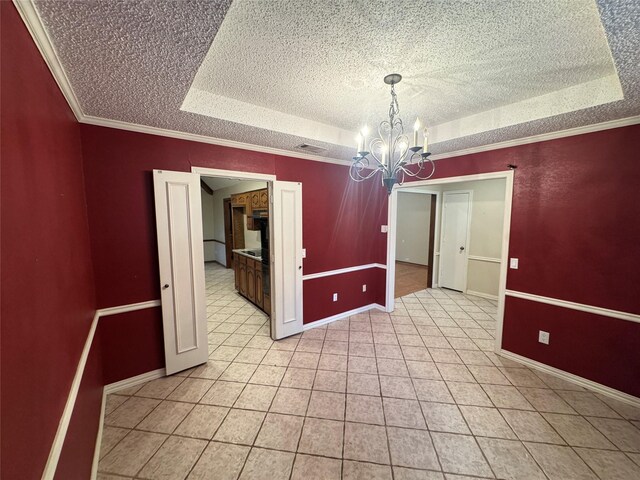 empty room featuring a textured ceiling, a chandelier, ornamental molding, a tray ceiling, and light tile patterned flooring