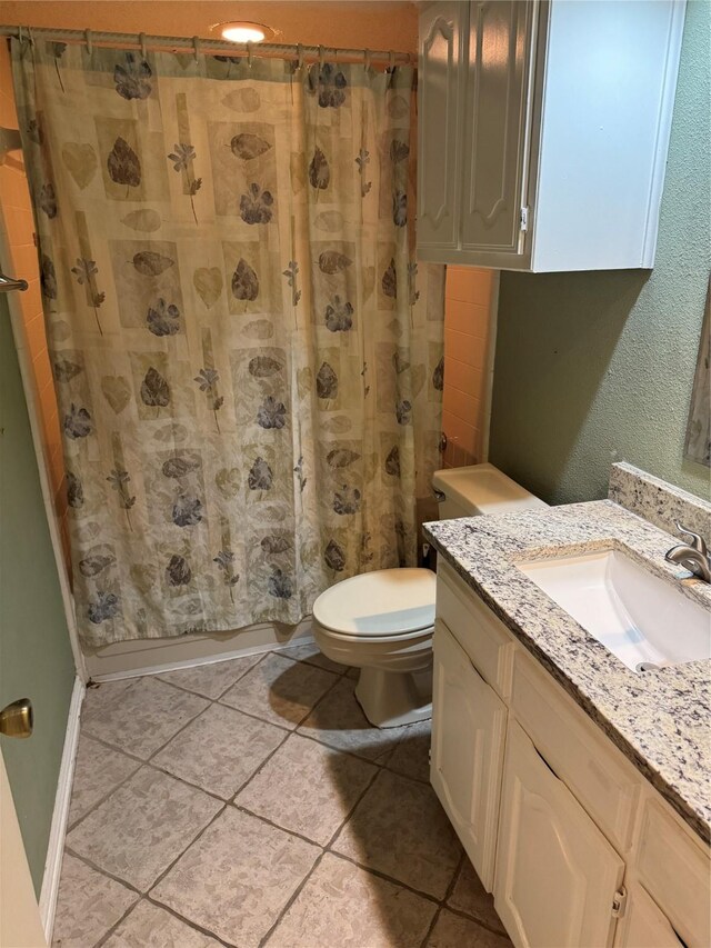 full bath with tile patterned floors, shower / bathtub combination with curtain, vanity, and toilet