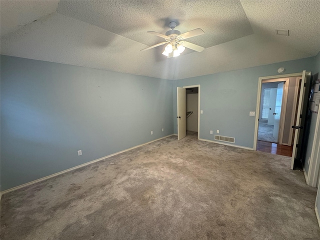 unfurnished bedroom featuring visible vents, lofted ceiling, baseboards, a textured ceiling, and carpet flooring