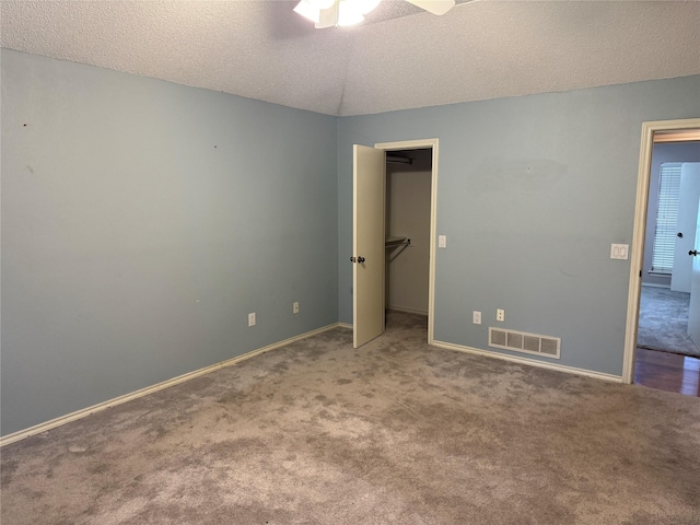 unfurnished bedroom featuring carpet floors, baseboards, a textured ceiling, and visible vents
