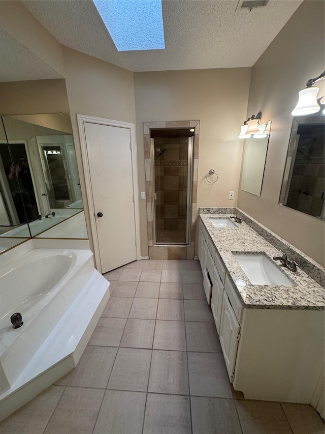bathroom featuring a textured ceiling, a skylight, a sink, and a stall shower