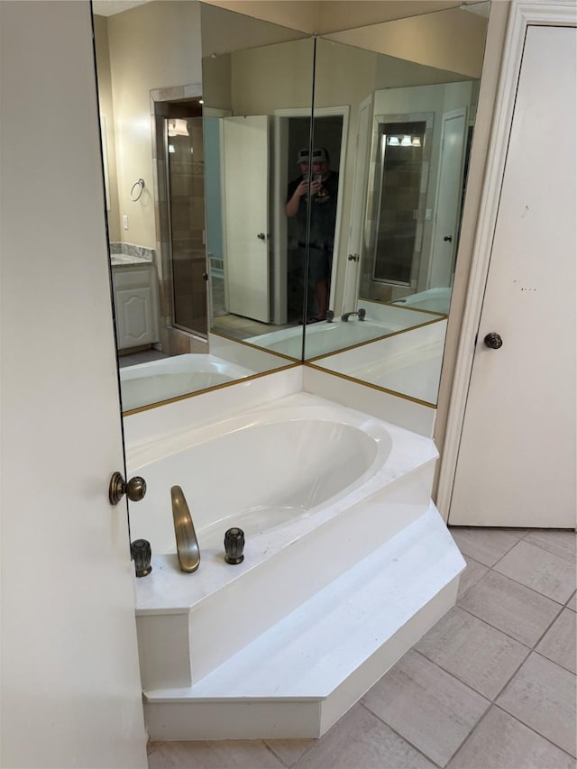 bathroom featuring tile patterned flooring, a shower stall, a garden tub, and vanity