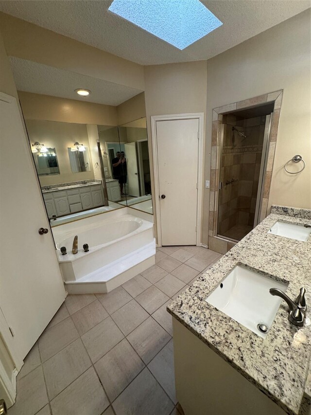 bathroom with a skylight, double vanity, a stall shower, and a sink