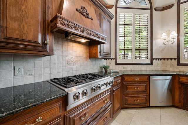 5404 Miramar Ln, Colleyville, TX 76034 - kitchen featuring stainless steel gas cooktop, premium range hood, decorative backsplash, light tile patterned floors, and dark stone countertops