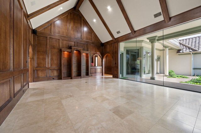 5404 Miramar Ln, Colleyville, TX 76034 - unfurnished living room featuring beamed ceiling, high vaulted ceiling, decorative columns, wooden walls, and arched walkways