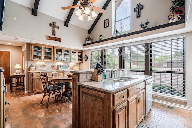 kitchen with a sink, high vaulted ceiling, an island with sink, decorative backsplash, and visible vents