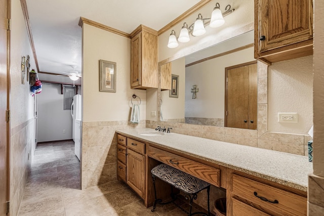 bathroom featuring vanity, ornamental molding, wainscoting, tile patterned flooring, and tile walls