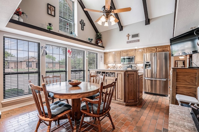 dining room featuring ceiling fan, beam ceiling, brick floor, high vaulted ceiling, and visible vents