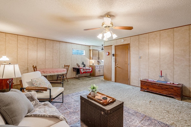 carpeted living area with a ceiling fan and a textured ceiling