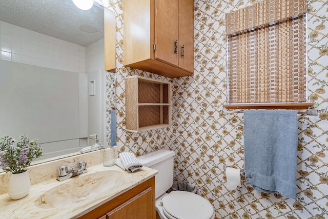 bathroom featuring vanity, a textured ceiling, toilet, and wallpapered walls