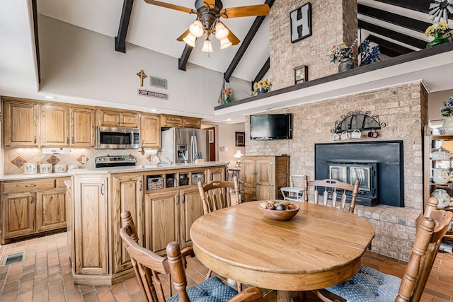 dining room with ceiling fan, visible vents, lofted ceiling with beams, and brick floor