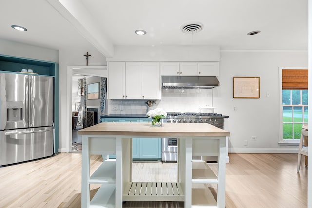 kitchen featuring decorative backsplash, white cabinetry, under cabinet range hood, light wood finished floors, and appliances with stainless steel finishes