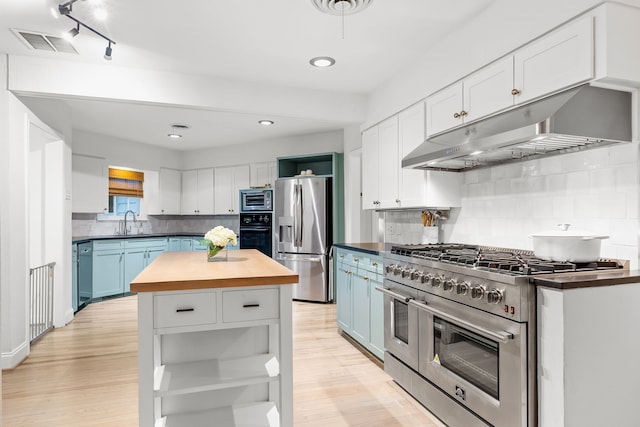 kitchen with under cabinet range hood, stainless steel appliances, open shelves, and butcher block countertops