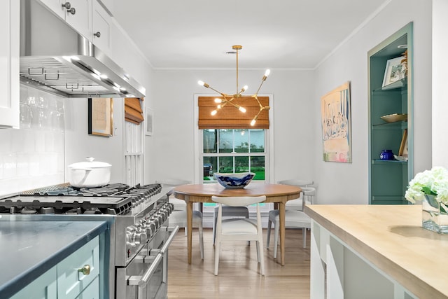 kitchen with an inviting chandelier, ornamental molding, light wood-style floors, under cabinet range hood, and double oven range