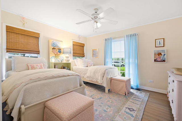 bedroom featuring baseboards, ornamental molding, wood finished floors, and multiple windows