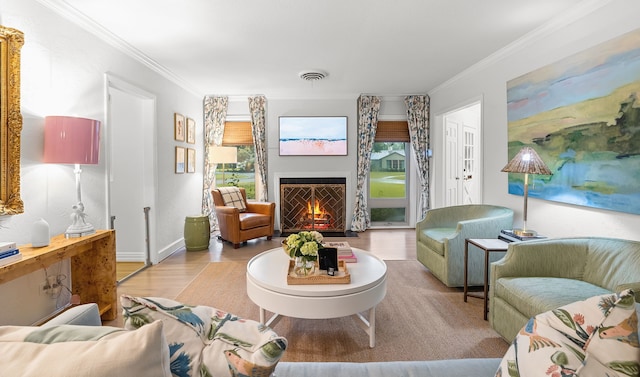 living area with visible vents, ornamental molding, wood finished floors, and a warm lit fireplace