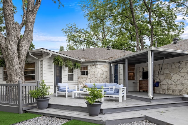 rear view of house with roof with shingles, outdoor lounge area, a wooden deck, and stone siding