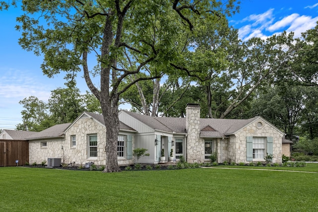 ranch-style house with roof with shingles, a chimney, a front lawn, and stone siding