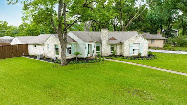 ranch-style home featuring fence, a front yard, stone siding, cooling unit, and a chimney