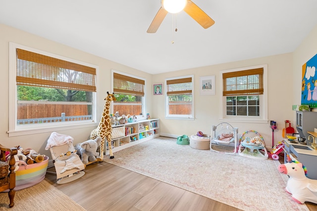 rec room with baseboards, ceiling fan, a healthy amount of sunlight, and wood finished floors