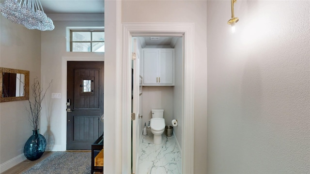 bathroom featuring toilet, baseboards, and a chandelier