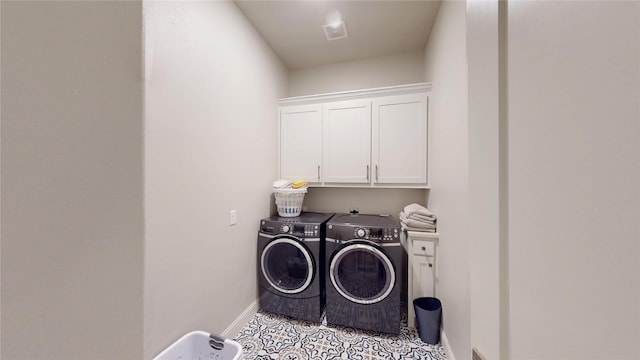 clothes washing area with baseboards, washing machine and dryer, cabinet space, and visible vents