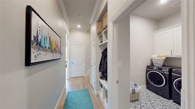clothes washing area featuring visible vents, washing machine and dryer, cabinet space, light wood finished floors, and ornamental molding