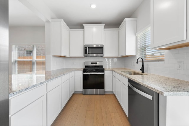 1203 Dye Blvd, Princeton, TX 75407 - kitchen with light wood-style floors, white cabinets, light stone counters, a sink, and appliances with stainless steel finishes