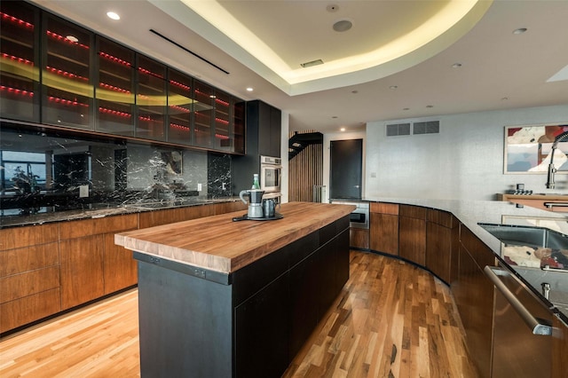 3111 Welborn St Unit 1703, Dallas, TX 75219 - bar featuring appliances with stainless steel finishes, decorative backsplash, visible vents, and light wood-style floors