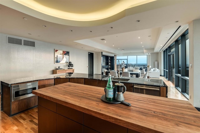 3111 Welborn St Unit 1703, Dallas, TX 75219 - kitchen with butcher block countertops, recessed lighting, open floor plan, wood finished floors, and a tray ceiling