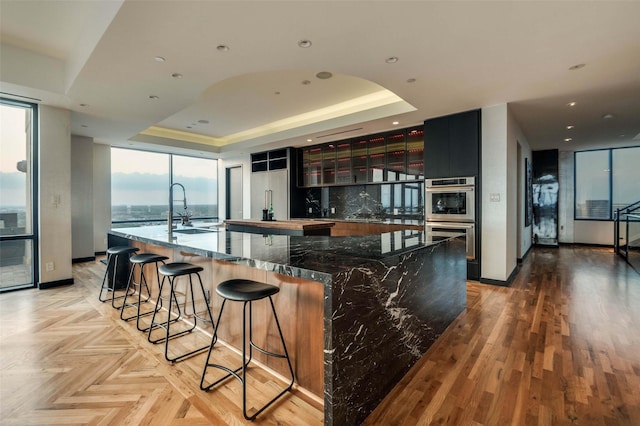 3111 Welborn St Unit 1703, Dallas, TX 75219 - kitchen with a sink, double oven, floor to ceiling windows, a tray ceiling, and a spacious island
