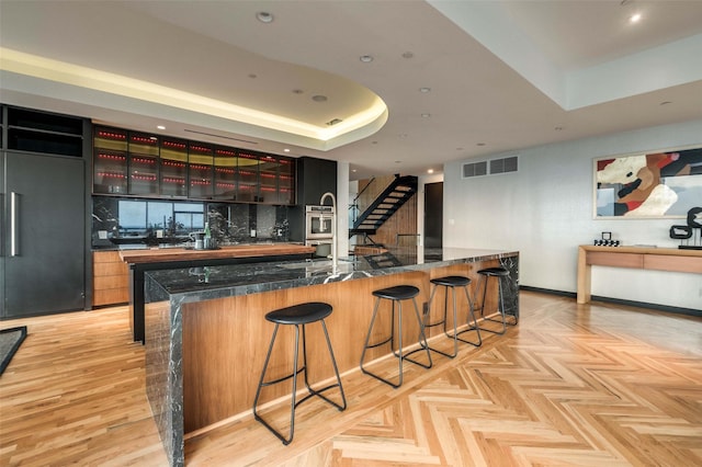 3111 Welborn St Unit 1703, Dallas, TX 75219 - kitchen with visible vents, dark countertops, a kitchen breakfast bar, built in refrigerator, and a tray ceiling